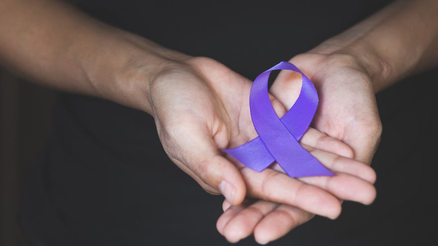 Two hands holding a purple ribbon representing domestic violence awareness.