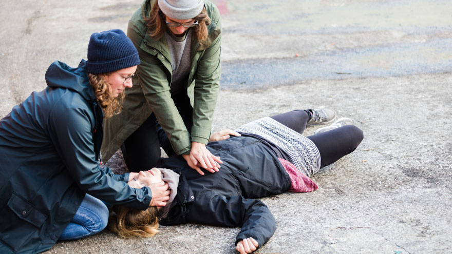 Two woman performing CPR on a woman in distress