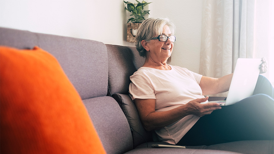 senior woman sitting on couch using laptop
