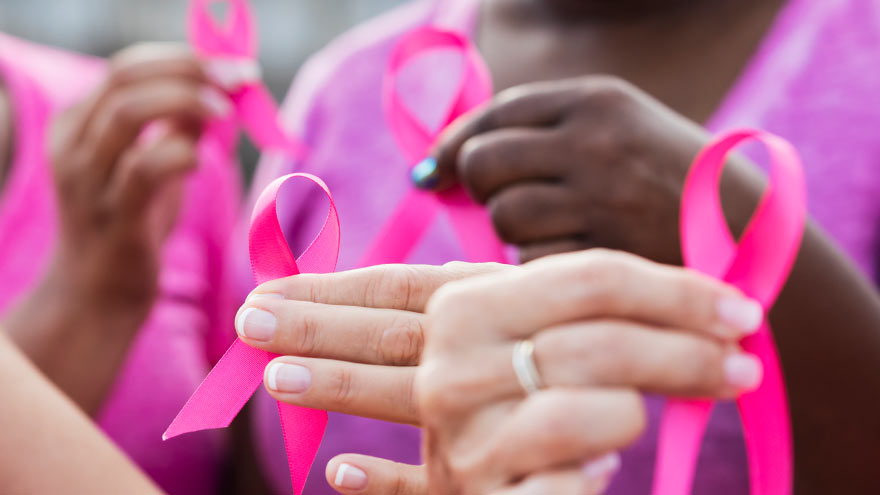 Group of women supporting breast cancer with pink ribbons in their hands