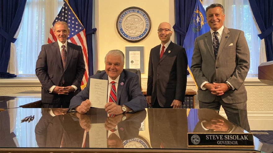 Nevada Governor Steve Sisolak holding up signed Senate Bill 342